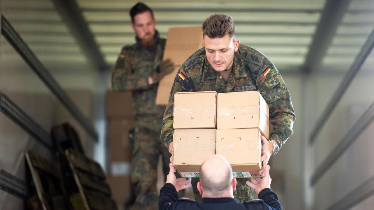 Soldaten und Feuerwehrmänner verladen Kartons mit Schutzkleidung in der Feuerwache. Die Bundeswehr unterstützt die Versorgung des Kreises Heinsberg mit 3.000 FFP2-Masken, 15.000 Mund-und Nasenschutzmasken und 8.000 Schutzkitteln, sowie 2 Intensiv-Beatmungsgeräten. Heinsbeg ist besonders stark von der Corona-Epidemie betroffen. Soldaten und Feuerwehrmänner verladen Kartons mit Schutzkleidung in der Feuerwache. Die Bundeswehr unterstützt die Versorgung des Kreises Heinsberg mit 3.000 FFP2-Masken, 15.000 Mund-und Nasenschutzmasken und 8.000 Schutzkitteln, sowie 2 Intensiv-Beatmungsgeräten. Heinsbeg ist besonders stark von der Corona-Epidemie betroffen.
