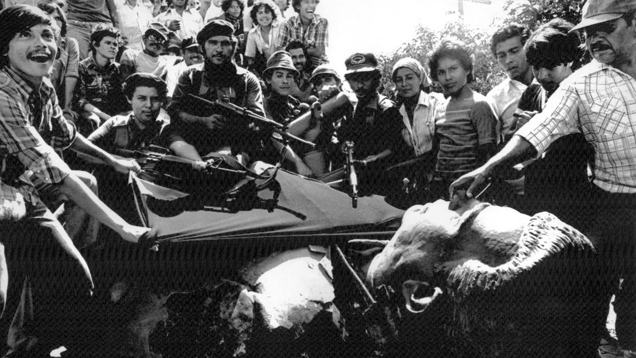 Sandinisten nach ihrem Sieg am 19. Juli 1979 in Managua neben einer umgestürzten Statue von Anastasio Somoza Garcia, dem Vater des besiegten Diktators Anastasio Somoza Debayle. Sandinisten nach ihrem Sieg am 19. Juli 1979 in Managua neben einer umgestürzten Statue von Anastasio Somoza Garcia, dem Vater des besiegten Diktators Anastasio Somoza Debayle.
