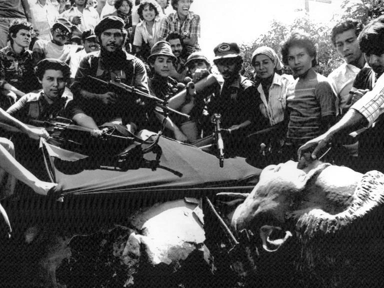 Sandinisten nach ihrem Sieg am 19. Juli 1979 in Managua neben einer umgestürzten Statue von Anastasio Somoza Garcia, dem Vater des besiegten Diktators Anastasio Somoza Debayle.