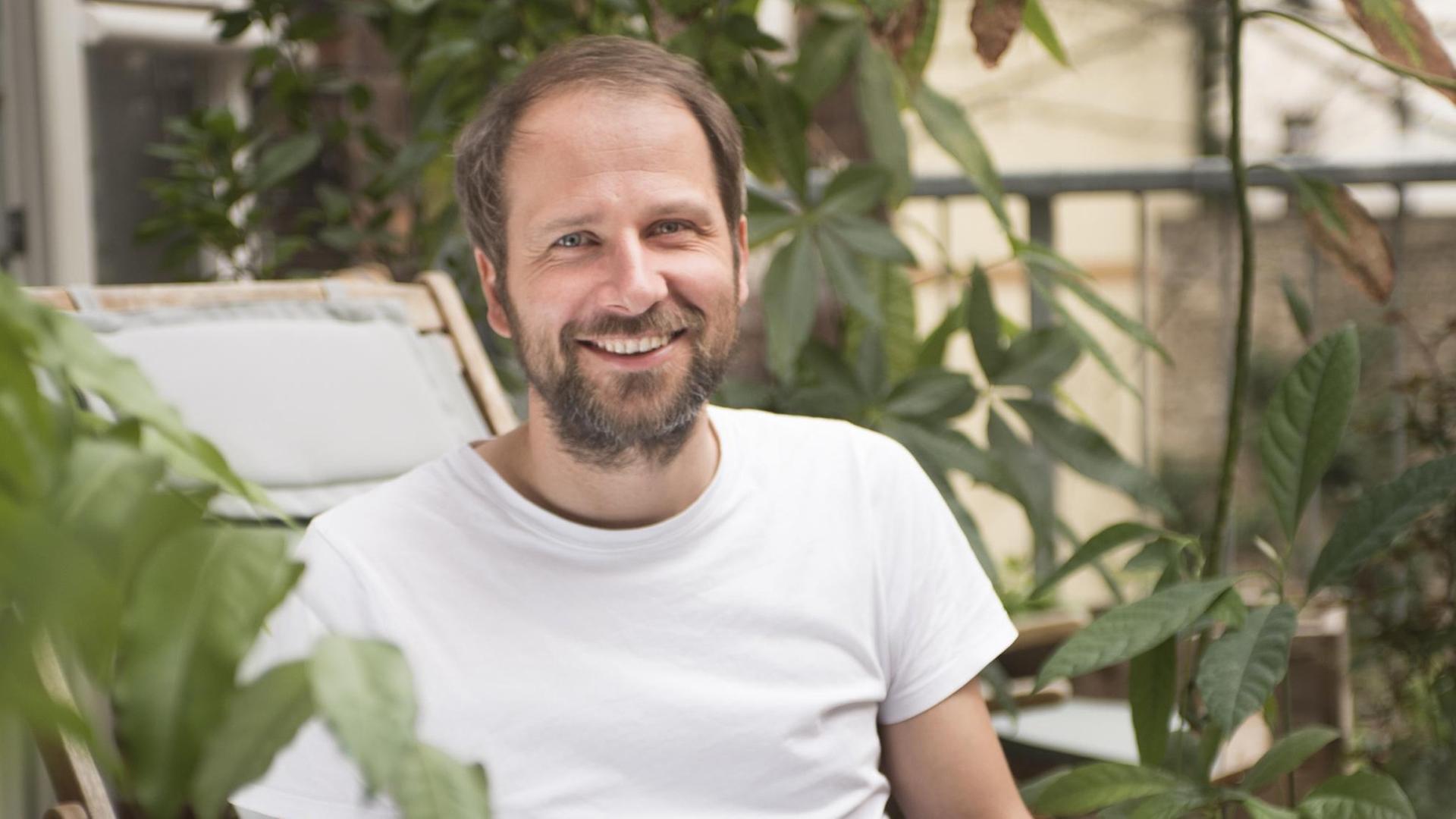 Christian Kroll, Gründer der grünen Suchmaschine "Ecosia" sitzt mit Laptop im Freien. Christian Kroll, Gründer der grünen Suchmaschine "Ecosia" sitzt mit Laptop im Freien.