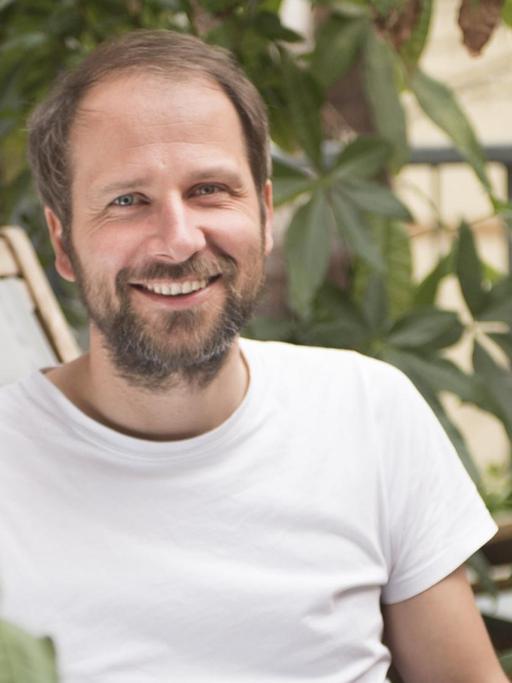 Christian Kroll, Gründer der grünen Suchmaschine "Ecosia" sitzt mit Laptop im Freien.
