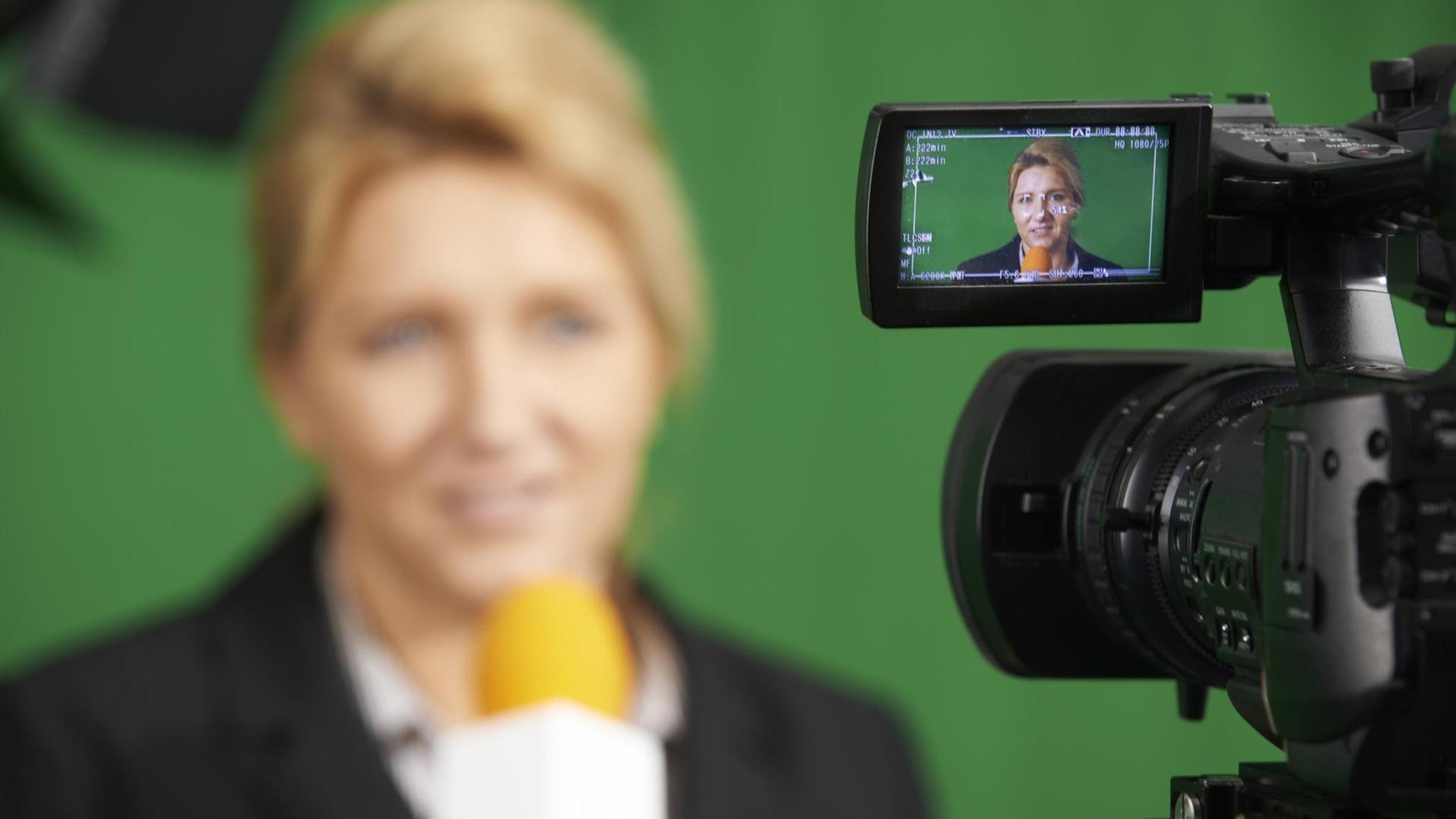 Moderatorin im Fernsehstudio durch die Anzeige einer Kamera gesehen (Symbolfoto). Moderatorin im Fernsehstudio durch die Anzeige einer Kamera gesehen (Symbolfoto).