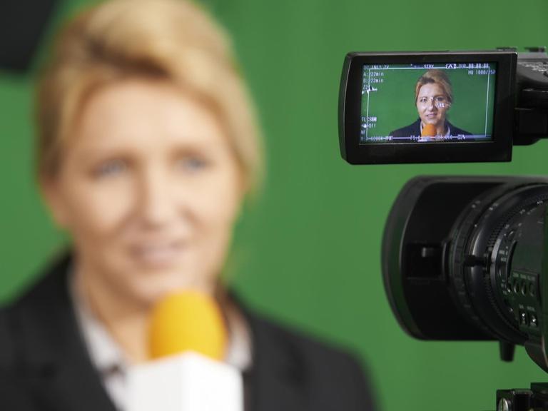 Moderatorin im Fernsehstudio durch die Anzeige einer Kamera gesehen (Symbolfoto).