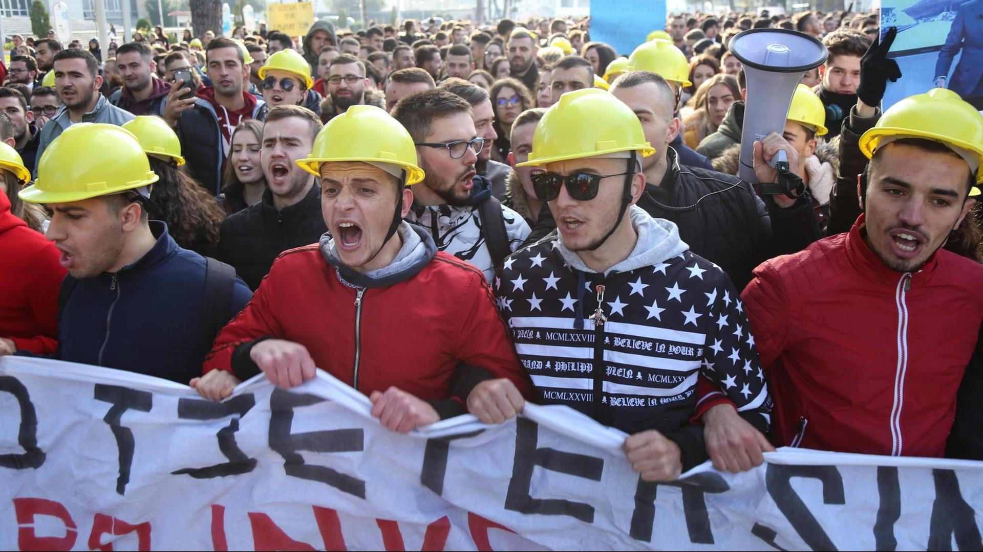 Studierende protestieren am 11.12.2018 vor dem Erziehungsministerium in Tirana, Albanien für bessere Studienbedingungen. Einige Demonstranten tragen gelbe Schutzhelme