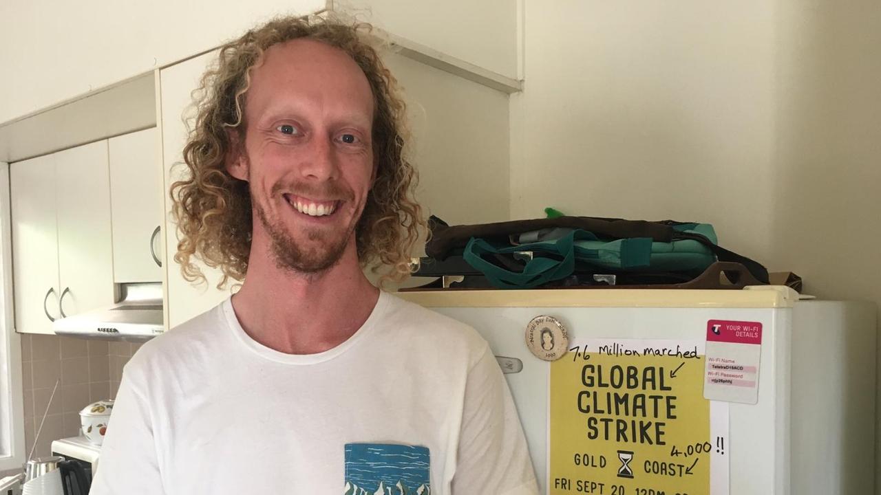 Zu sehen ist ein Mann mit längeren, blonden Locken, der vor einem Kühlschrank steht. Am Kühlschrank hängt ein Plakat, was auf den Global Klimastreik an der Gold Coast in Australien aufmerksam macht. Zu sehen ist ein Mann mit längeren, blonden Locken, der vor einem Kühlschrank steht. Am Kühlschrank hängt ein Plakat, was auf den Global Klimastreik an der Gold Coast in Australien aufmerksam macht.