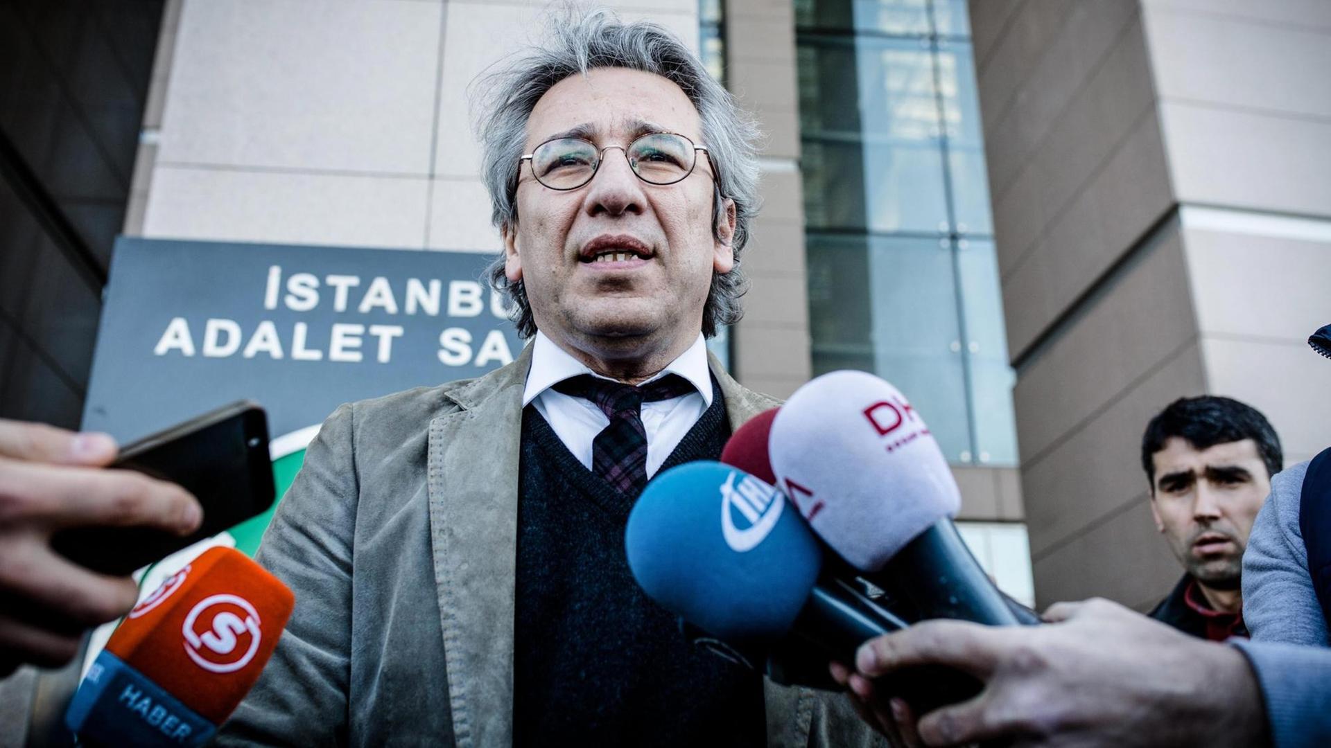 Can Dündar spricht in mehrere Mikrofone. Sein Gesichtsausdruck ist ernst. Can Dündar spricht in mehrere Mikrofone. Sein Gesichtsausdruck ist ernst.