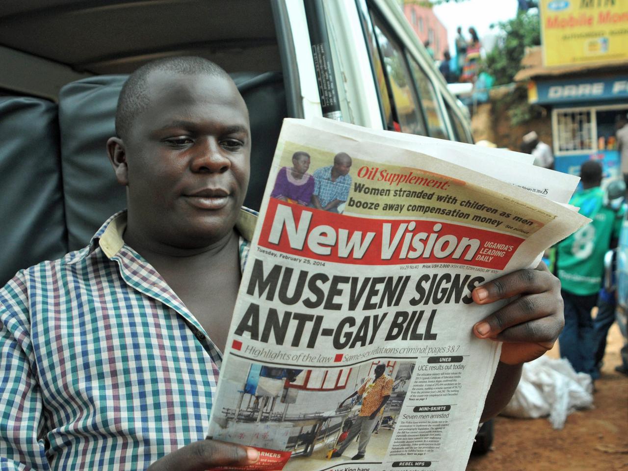Mann liest eine Zeitung vom 25.02.2014 mit der Schlagzeile "Museveni signs anti-gay bill". Am 24.02.2014 hatte Ugandas Präsident Yoweri Museveni ein Anti-Schwulen-Gesetz unterschrieben.