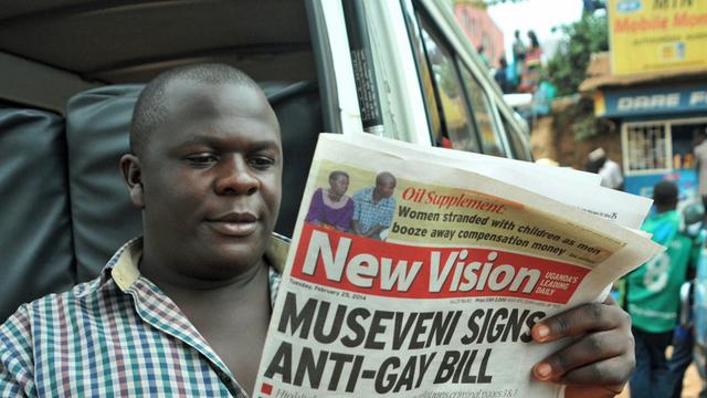 Mann liest eine Zeitung vom 25.02.2014 mit der Schlagzeile "Museveni signs anti-gay bill". Am 24.02.2014 hatte Ugandas Präsident Yoweri Museveni ein Anti-Schwulen-Gesetz unterschrieben.