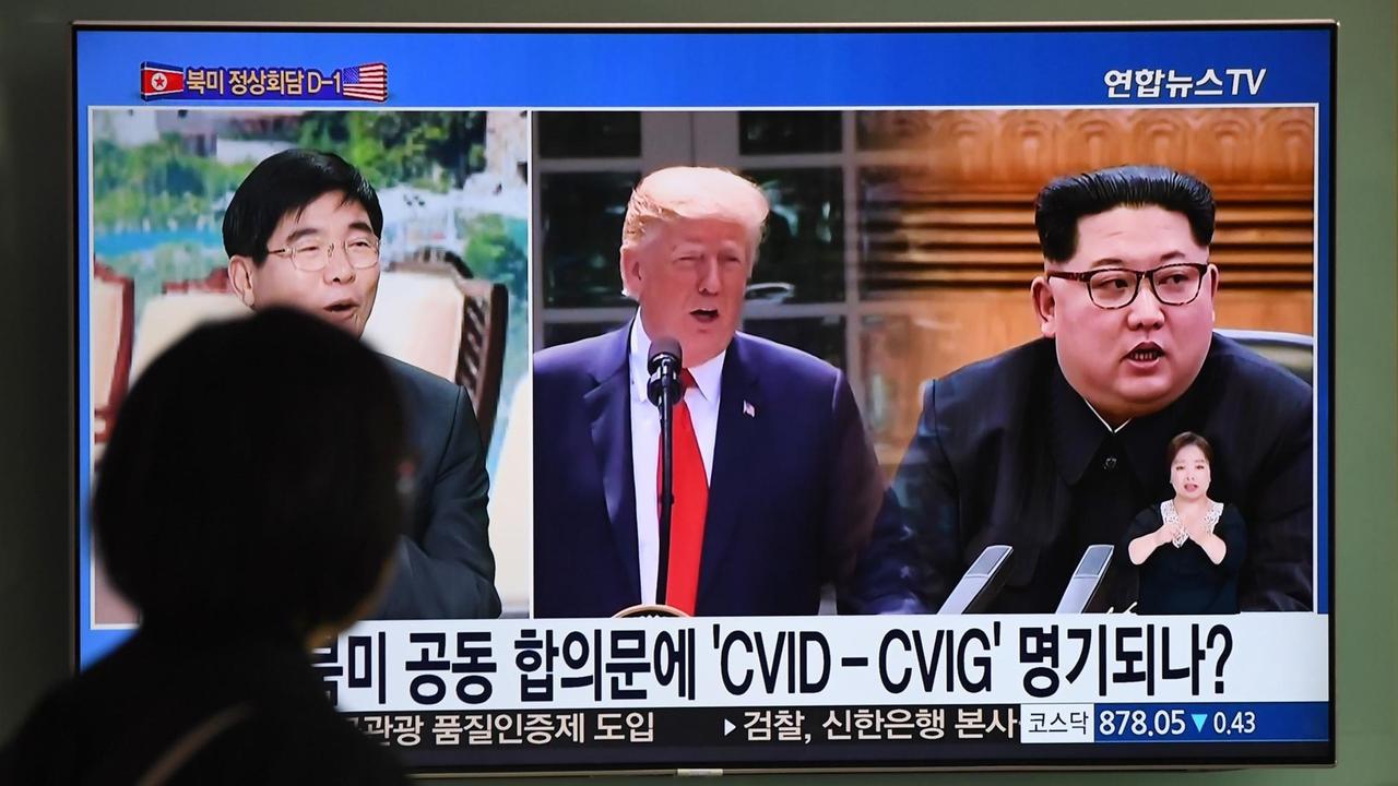 Fernsehbildschirm mit den Gesichtern von Donald Trump und Kim Jong Un an einem Bahnhof in Seoul