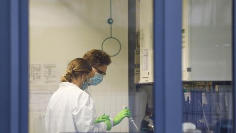 Blick durch ein Fenster der Firma Biontech. Zu sehen sind zwei Mitarbeiterinnen im Labor.