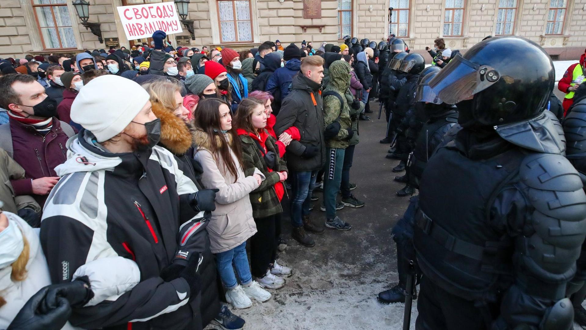 Russische Demonstranten und Polizisten stehen sich gegenüber. Auf einem Plakat steht "Freiheit für Nawalny". Russische Demonstranten und Polizisten stehen sich gegenüber. Auf einem Plakat steht "Freiheit für Nawalny".