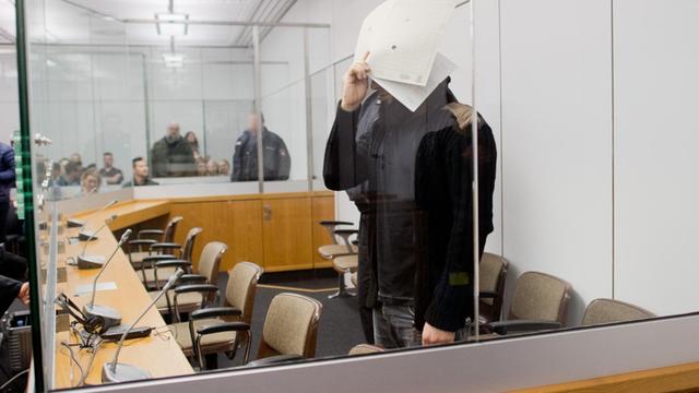 Der angeklagte Abu Walaa steht im Oberlandesgericht in Celle (Niedersachsen), er hält einen Ordner vor dem Gesicht