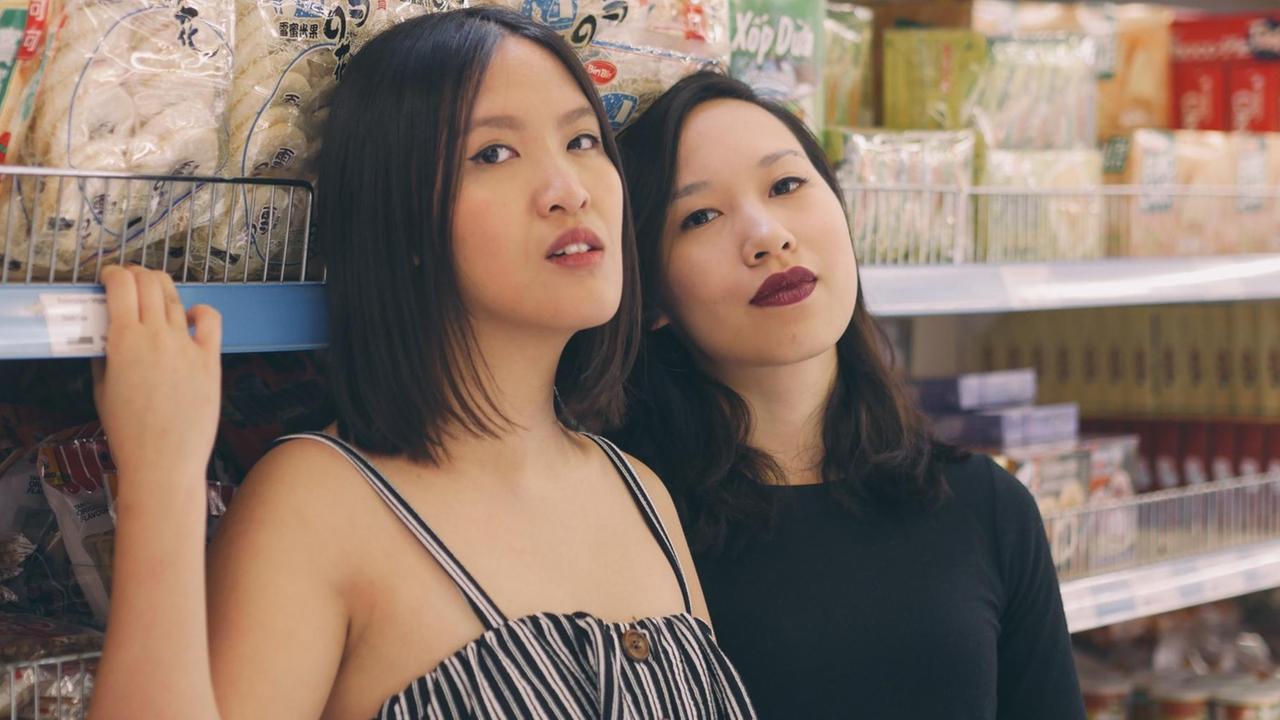Vanessa Vu (rechts) und Minh Thu Tran (links) lehnen an einem Supermarkt-Regal mit asiatischen Lebensmitteln. Vanessa Vu (rechts) und Minh Thu Tran (links) lehnen an einem Supermarkt-Regal mit asiatischen Lebensmitteln.
