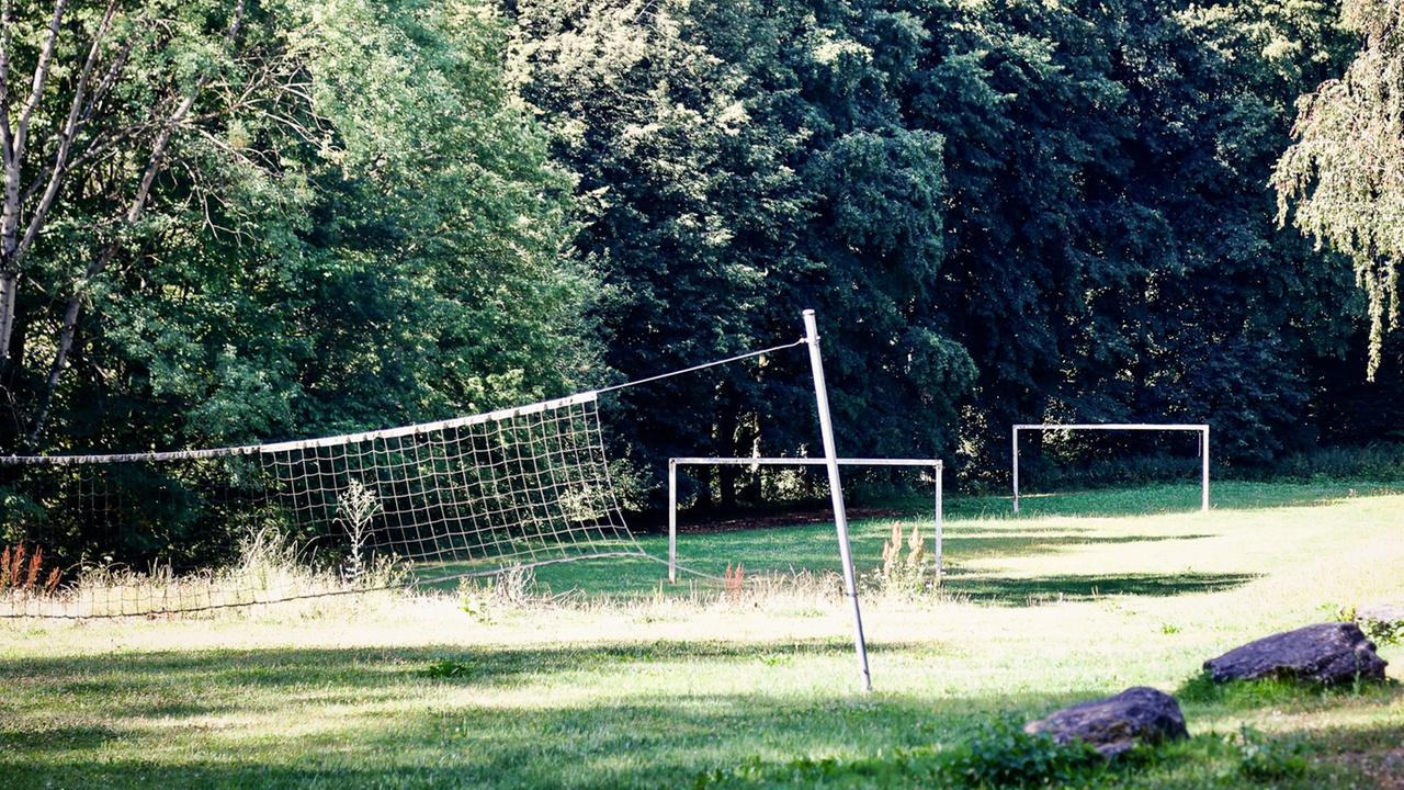 Blick auf eine Sportanlage mit Fußballtoren und Volleyballnetz im Freien.