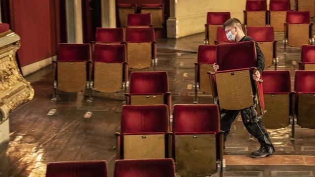 Ein Mann entfernt Stühle aus dem Zuschauerraum eines Theaters