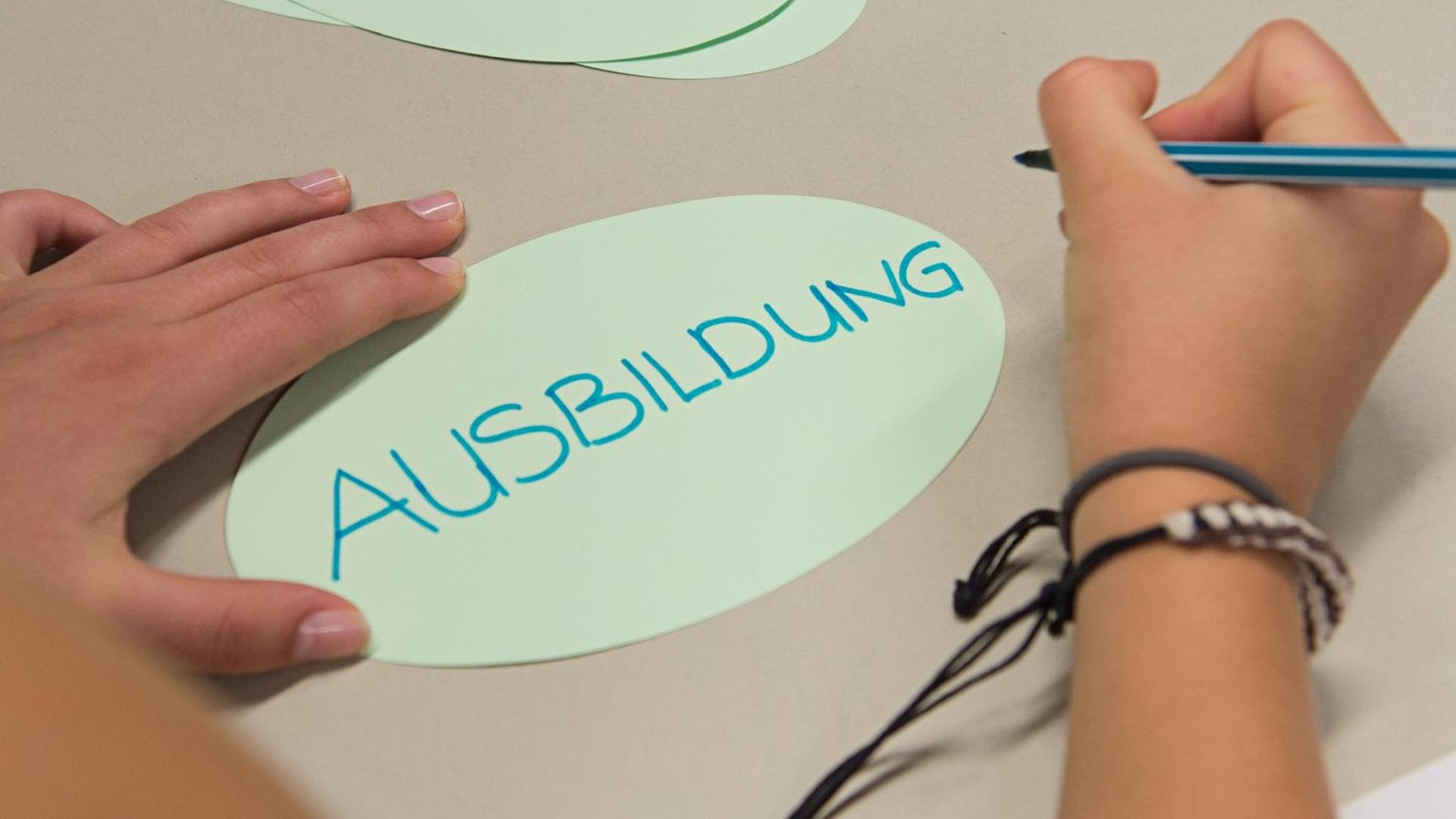 Ein Zettel mit der Aufschrift "Ausbildung" liegt auf einem Tisch vor einer Schülerin Ein Zettel mit der Aufschrift "Ausbildung" liegt auf einem Tisch vor einer Schülerin