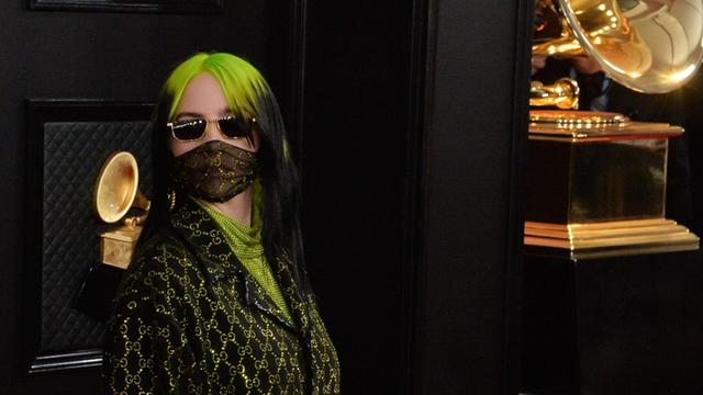 Eine vermummte Frau mit grünen Haaren und Sonnenbrille