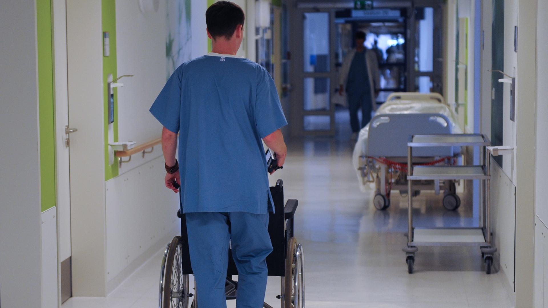 Ein Pfleger schiebt einen Rollstuhl durch einen Krankenhausflur. Ein Pfleger schiebt einen Rollstuhl durch einen Krankenhausflur.