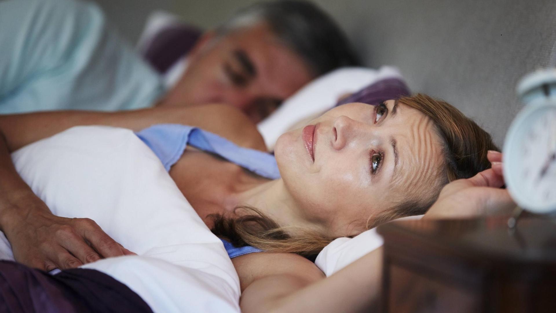 Eine Frau liegt mit Schlafproblemen im Bett. Eine Frau liegt mit Schlafproblemen im Bett.
