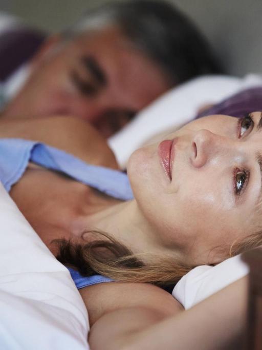 Eine Frau liegt mit Schlafproblemen im Bett.