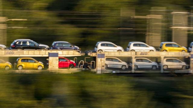 Ein fahrender Güterzug hat Autos der Marke VW geladen