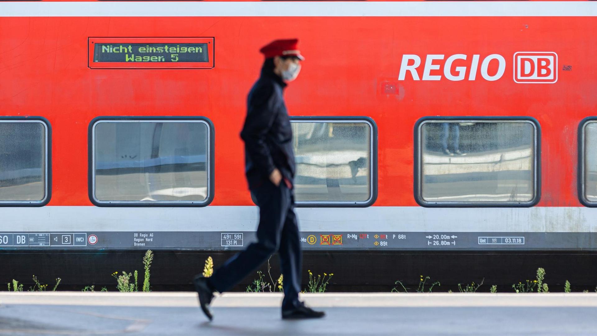 Ein Mitarbeiter von der Bahn läuft vor einem Regional-Zug.