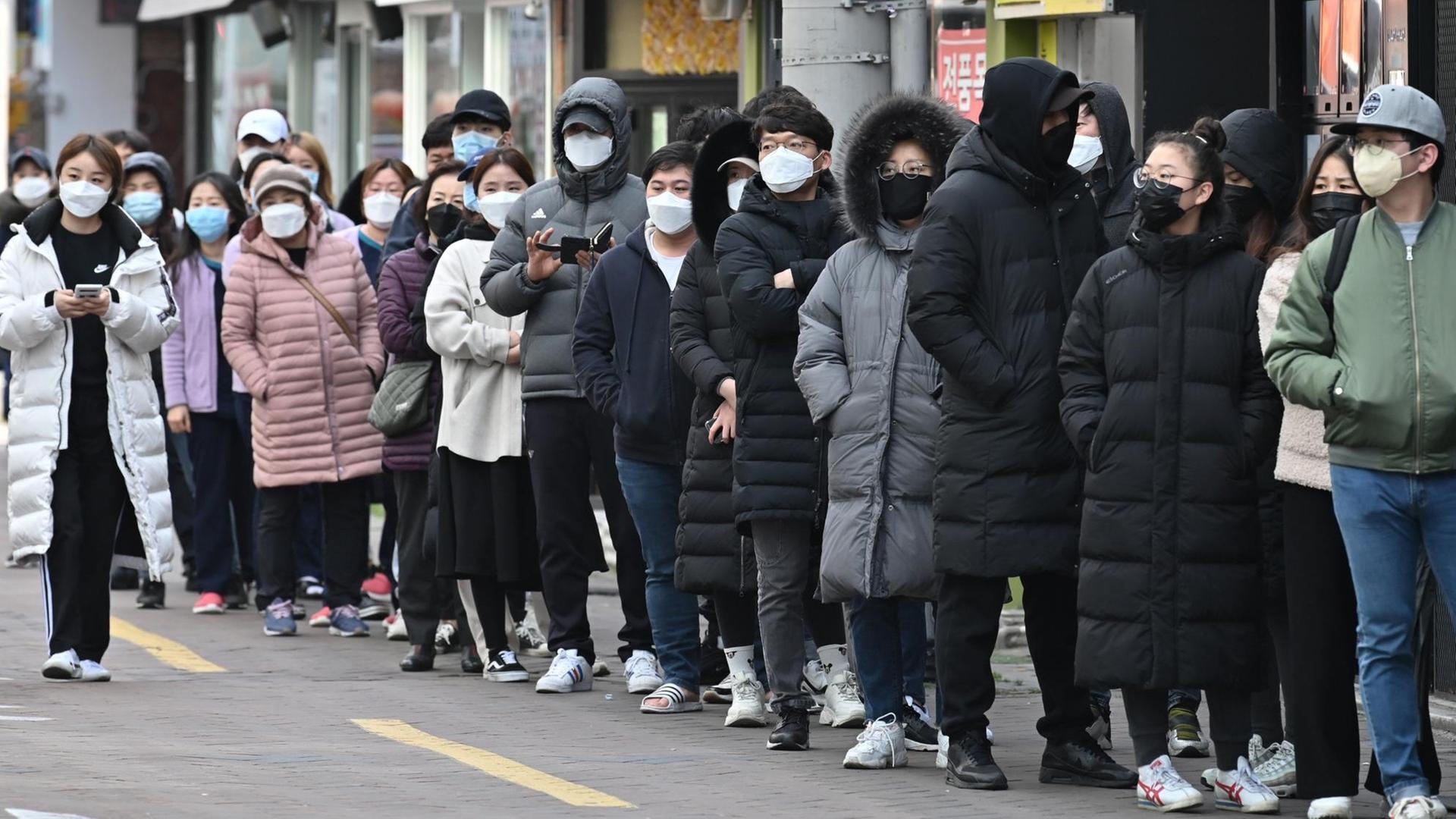 Menschen stehen vor einem Geschäft in Daegu Schlange, um Atemschutzmasken zu kaufen. Menschen stehen vor einem Geschäft in Daegu Schlange, um Atemschutzmasken zu kaufen.