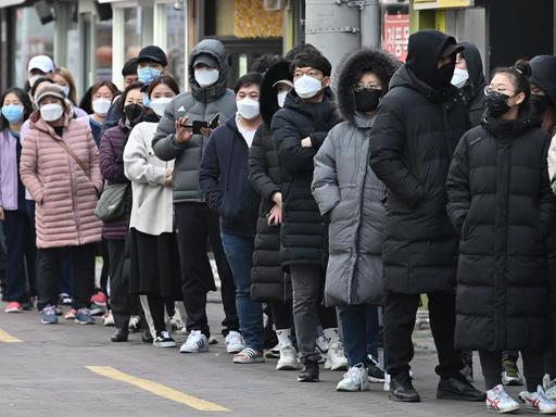 Menschen stehen vor einem Geschäft in Daegu Schlange, um Atemschutzmasken zu kaufen.