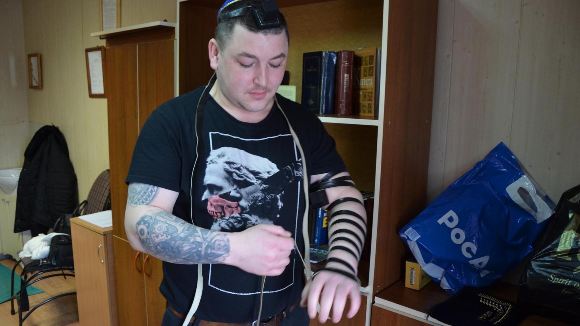 Ein gläubiger Häftling trägt zu Purin schwarze, lederne Gebetsriemen, die um Arm, Hand und Finger gebunden werden. Ein gläubiger Häftling trägt zu Purin schwarze, lederne Gebetsriemen, die um Arm, Hand und Finger gebunden werden.