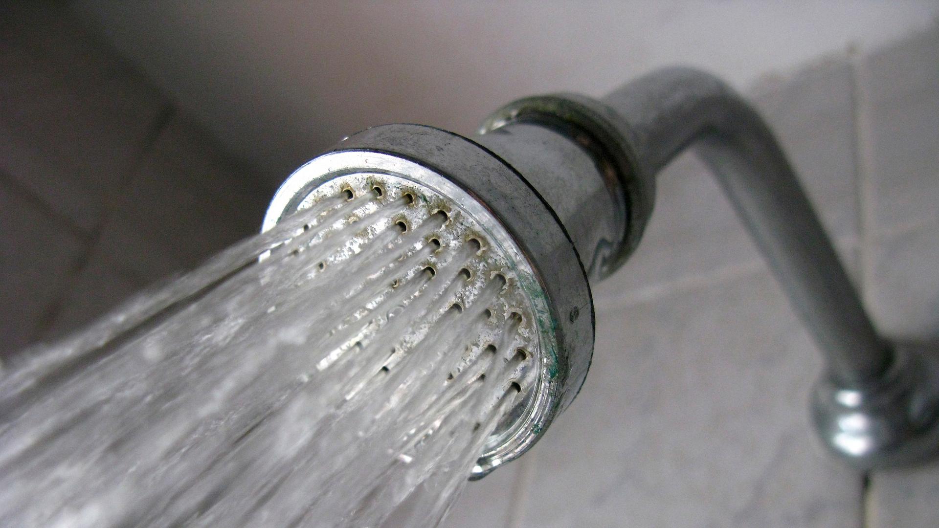 Wasser fließt durch einen Duschkopf Wasser fließt durch einen Duschkopf