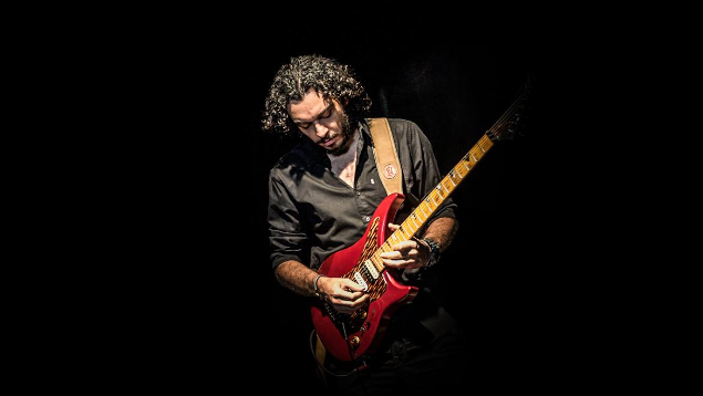 Der ägyptische Gitarrist Ousso ist der Inititator der Website Ewsal Bel3Araby spielt vor schwarzem Hintergrund Gitarre.