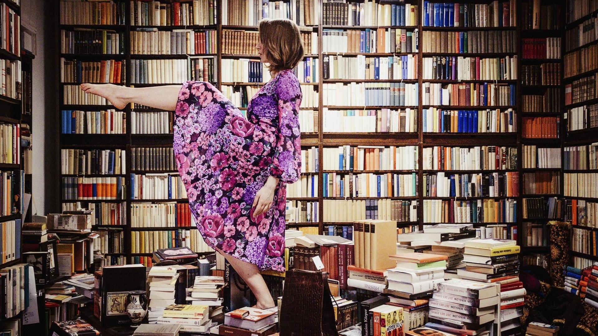 Eine Frau tanzt auf einem Stapel von Bücher mitten in einer Bibliothek. Eine Frau tanzt auf einem Stapel von Bücher mitten in einer Bibliothek.