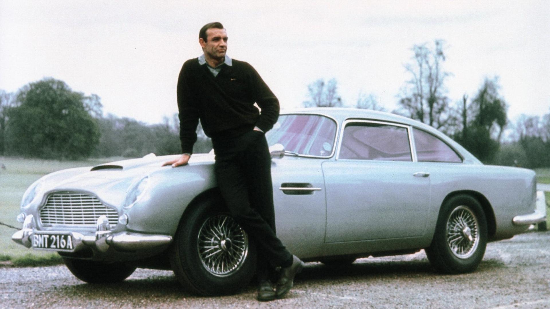 Sean Connery lässig an die Motorhaube eines Aston Martin DB5 gelehnt im Bond-Film Goldfinger aus dem Jahr 1964. Sean Connery lässig an die Motorhaube eines Aston Martin DB5 gelehnt im Bond-Film Goldfinger aus dem Jahr 1964.