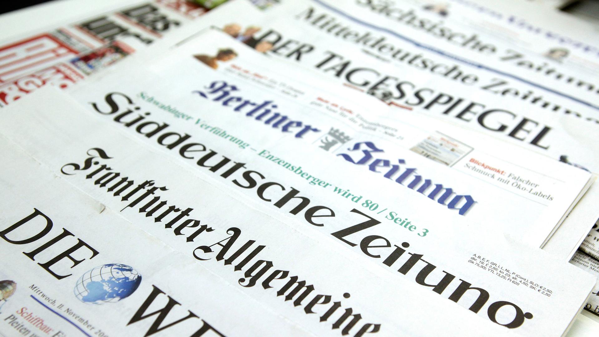 Auf einem Tisch liegen deutsche Tageszeitungen so versetzt, dass jeweils nur der Titel zu lesen ist, ganz vorne "Die Welt", "Frankfurter Allgemeine Zeitung" und "Süddeutsche Zeitung"