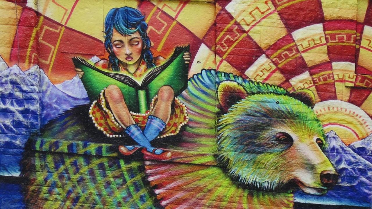 Eine Wandmalerei am Kensington Market in Toronto zeigt ein junges Mädchen, das ein Buch in der Hand hält und liest, während es auf dem Rücken eines Bären sitzt. Der Bär ist sehr bunt, wie auch der ganze Hintergrund. Eine Wandmalerei am Kensington Market in Toronto zeigt ein junges Mädchen, das ein Buch in der Hand hält und liest, während es auf dem Rücken eines Bären sitzt. Der Bär ist sehr bunt, wie auch der ganze Hintergrund.