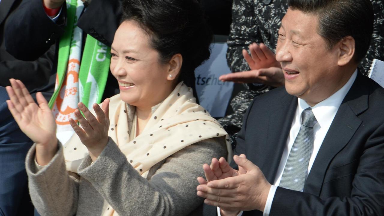 Der chinesische Staats- und Parteichef Xi Jinping (r) und seine Ehefrau Peng Liyuan applaudieren am 29.03.2014 im Olympiapark in Berlin während eines Fußball-Freundschaftsspiels zwischen einer chinesischen Jugendmannschaft und der Jugendauswahl des VfL Wolfsburg. Es : Soeren Stache/dpa |