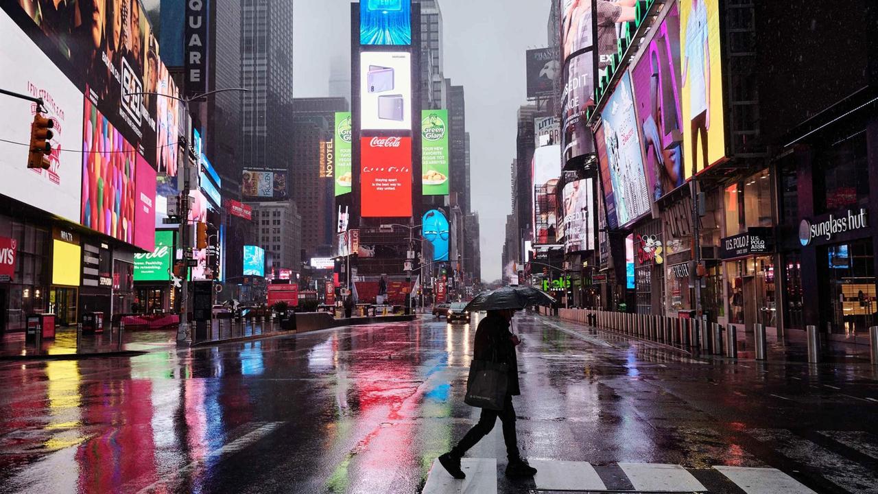 Der Times Square in New York City. Ein Passant überquert die Straße.