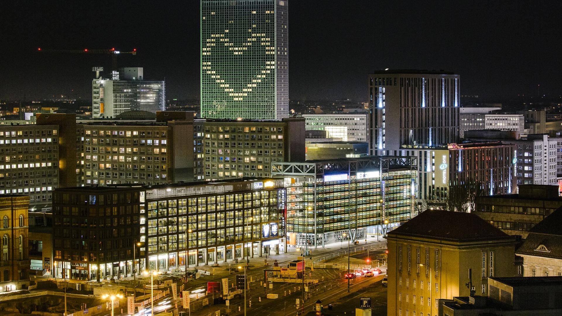 Eine Panoamansicht zeigt Berlin-Mitte am Abend. Im höchsten Gebäude, dem Hotel Park Inn, leuchtet in der Corona-Krise ein Herz geformt aus Lichtern der derzeit nicht buchbaren Hotelzimmer.