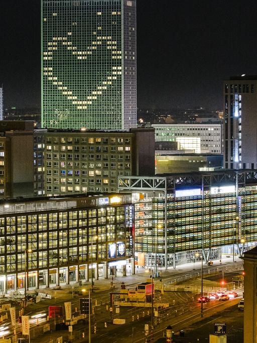 Eine Panoamansicht zeigt Berlin-Mitte am Abend. Im höchsten Gebäude, dem Hotel Park Inn, leuchtet in der Corona-Krise ein Herz geformt aus Lichtern der derzeit nicht buchbaren Hotelzimmer.