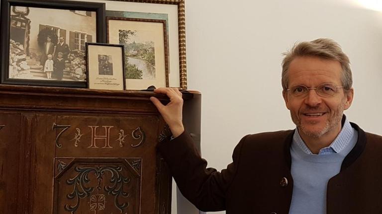 Florian Kohler steht neben einem antiken Schrank. Florian Kohler steht neben einem antiken Schrank.