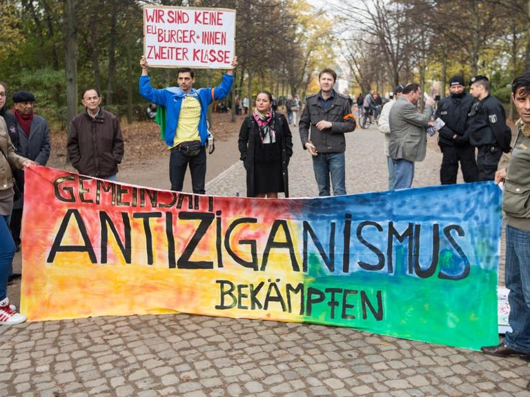 "Gemeinsam Antiziganismus bekämpfen" steht am 25.10.2013 vor dem Mahnmal für Sinti und Roma in Berlin bei einer Kundgebung auf einem Banner.