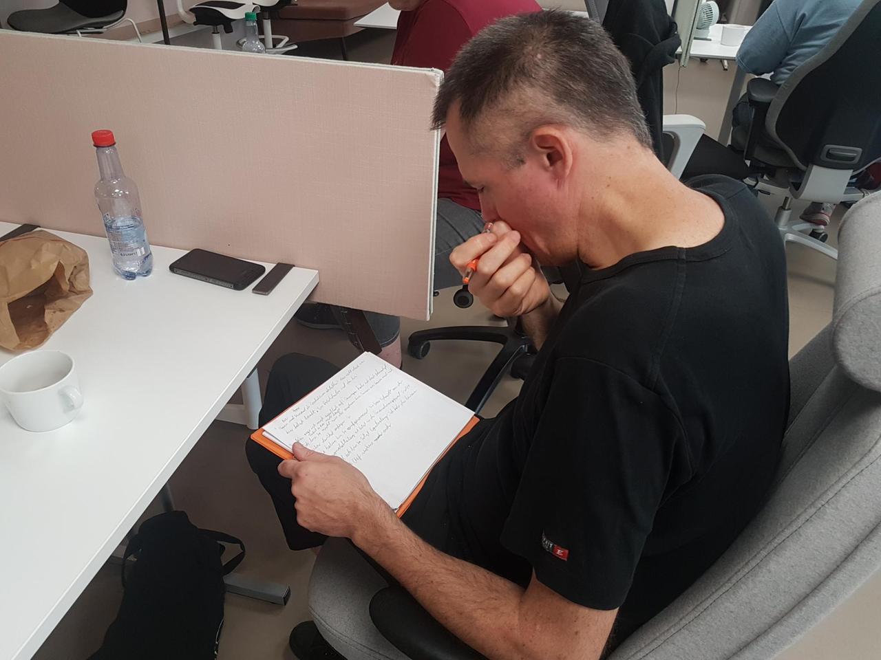  Ein Teilnehmer feilt an seinem Text. Er sitzt an einem Tisch und schaut konzentriert auf seine Notizen.