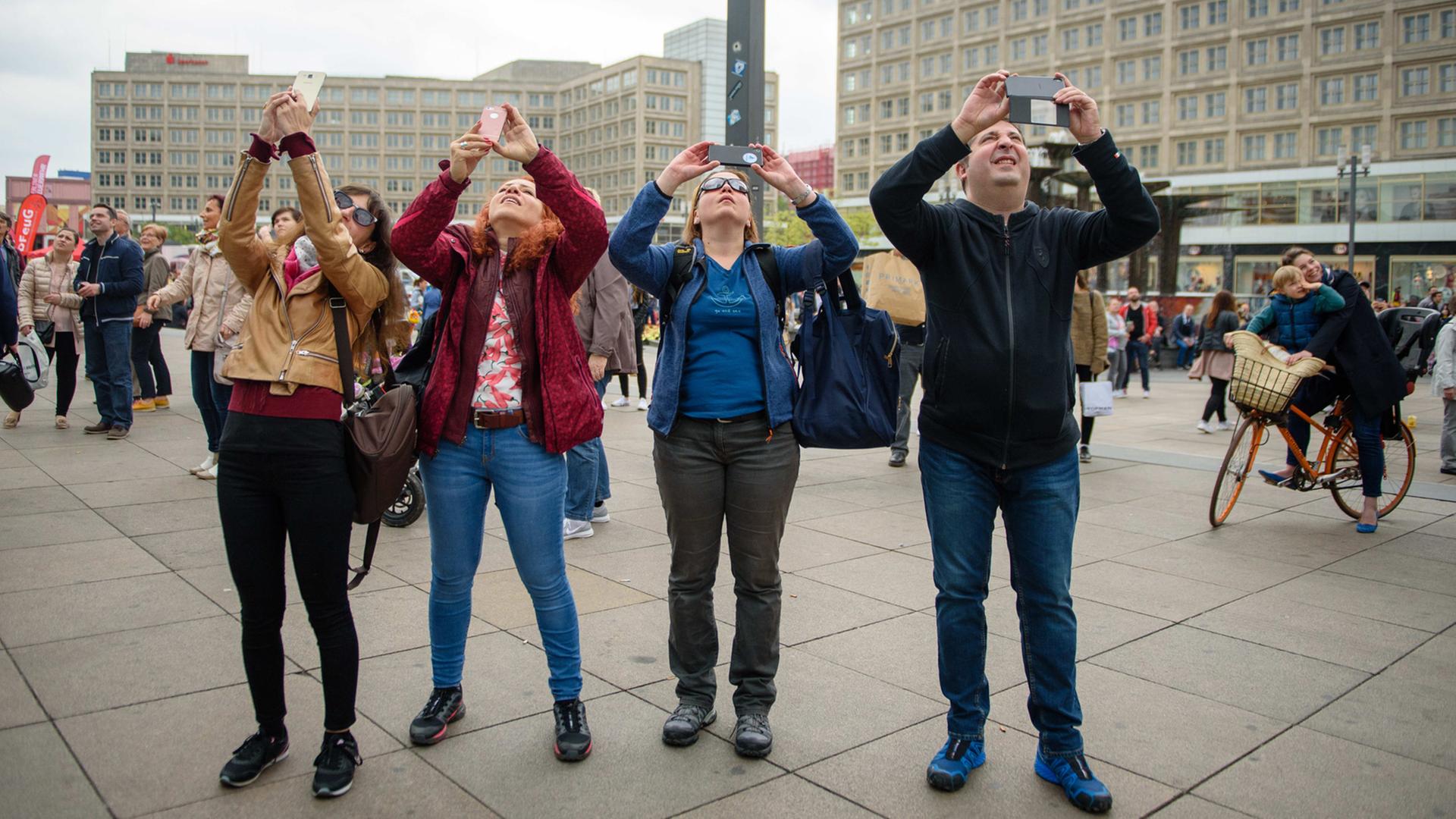 Touristen fotografieren mit ihren Smartphones ein Hochhaus auf dem Alexanderplatz in Berlin. Touristen fotografieren mit ihren Smartphones ein Hochhaus auf dem Alexanderplatz in Berlin.