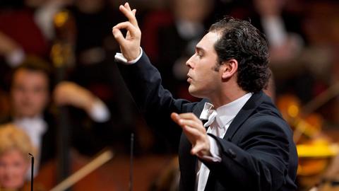 Der Dirigent Tugan Sokhiev beim Dirigat vor einem Orchester.