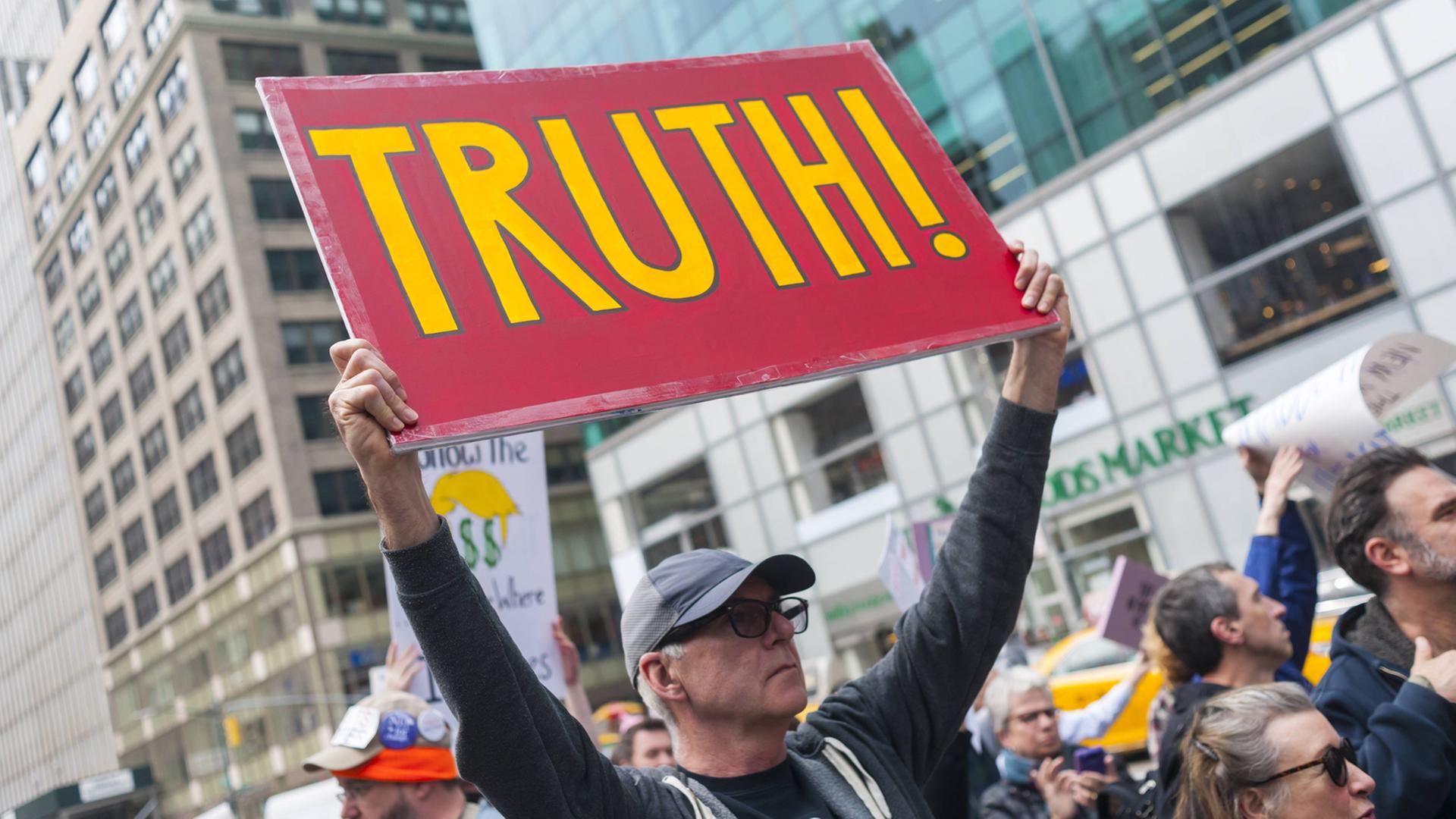 Ein Demonstrant hält ein Plakat mit der Aufschrift "Truth", Wahrheit hoch, bei dem Protestmarsch in New York in Reaktion auf Donald Trumps "Krieg gegen die Medien" Ein Demonstrant hält ein Plakat mit der Aufschrift "Truth", Wahrheit hoch, bei dem Protestmarsch in New York in Reaktion auf Donald Trumps "Krieg gegen die Medien"