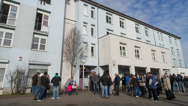 Zu sehen sind Asylbewerber in Karlsruhe vor einem Unterkunftsgebäude.