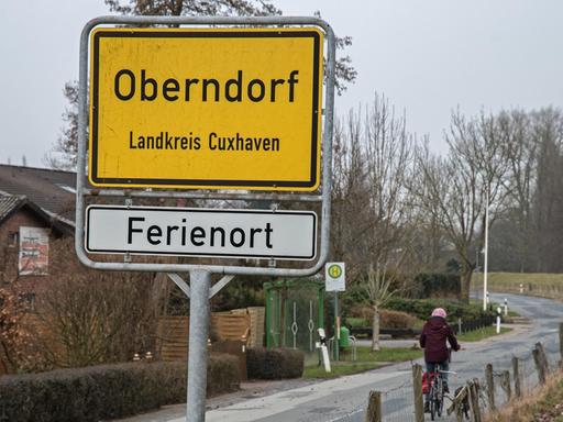 Eine Frau fährt am 08.03.2017 mit dem Fahrrad auf einer Landstraße am Ostedeich in den Ort Oberndorf (Niedersachsen).