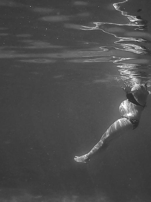 Unterwasserfoto einer schwangeren Frau.
