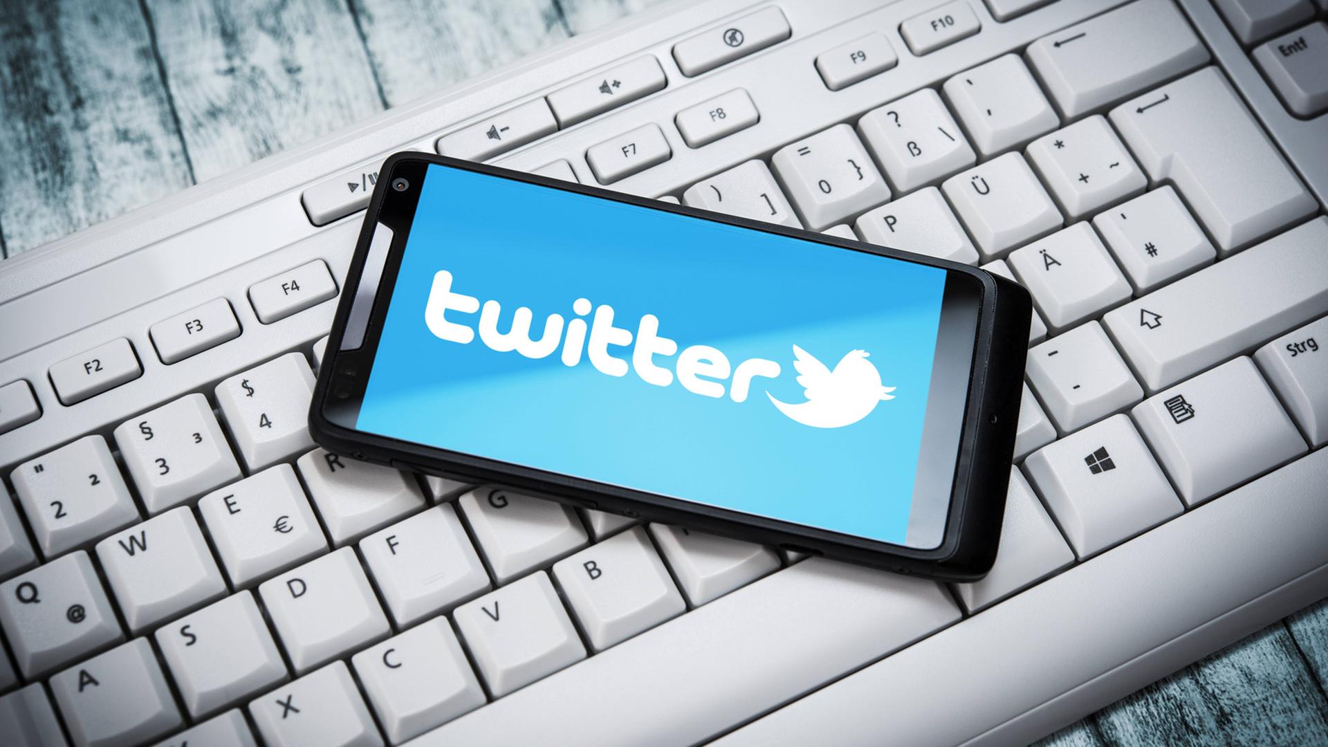 Smartphone mit Twitter-Logo auf Computertastatur Smartphone mit Twitter-Logo auf Computertastatur