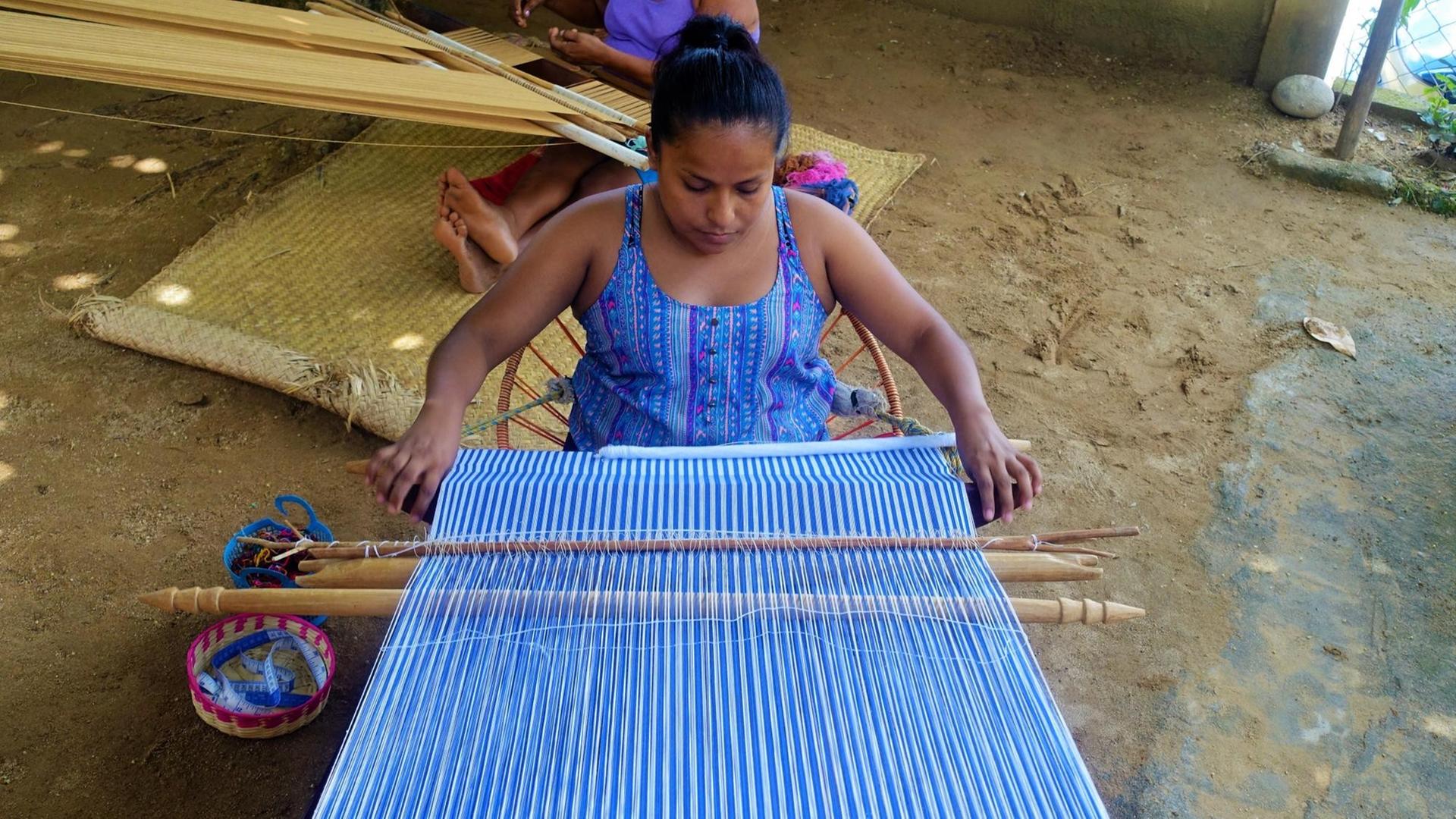 Indigene Weberin in San Juan arbeitet an einem Kleidungsstück an ihrer Maschine im Hof.